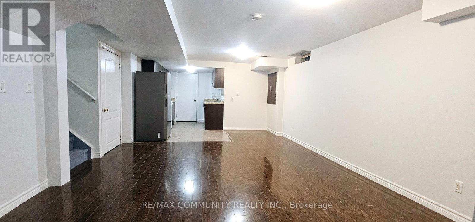 A long hallway with a refrigerator and a staircase.