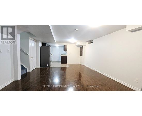 A long hallway with a refrigerator and a staircase.