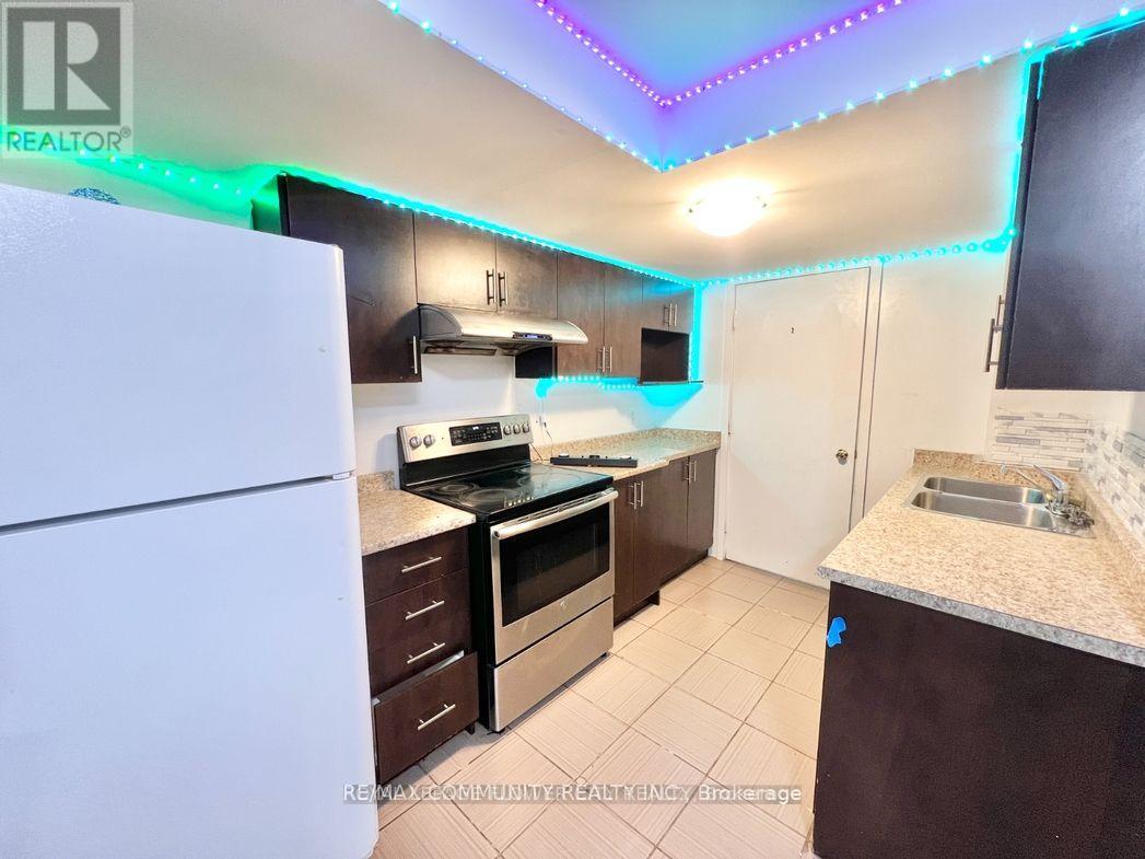 A kitchen with a white fridge, brown cabinets, and a counter with a sink.
