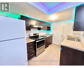 A kitchen with a white fridge, brown cabinets, and a counter with a sink.