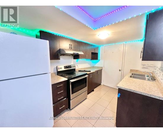 A kitchen with a white fridge, brown cabinets, and a counter with a sink.