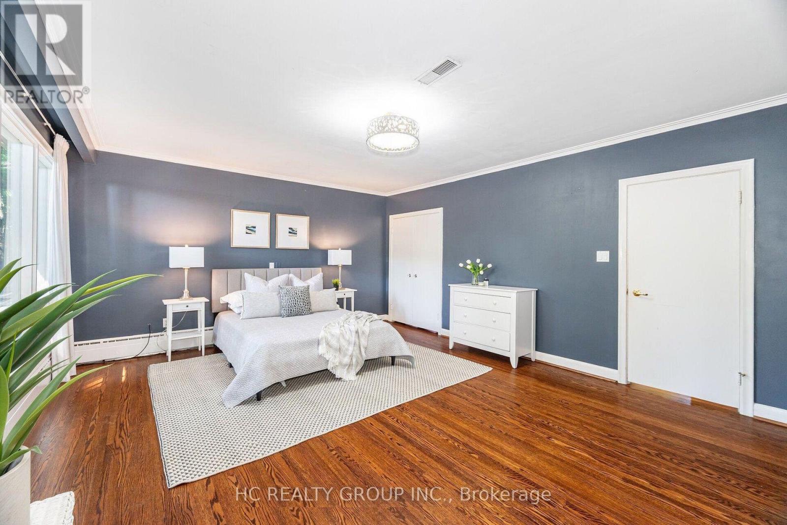 A bedroom with a bed, nightstands, and a plant.