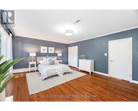 A bedroom with a bed, nightstands, and a plant.
