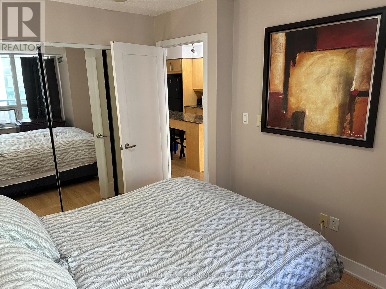 A bedroom with a bed, a mirror, and a painting on the wall.