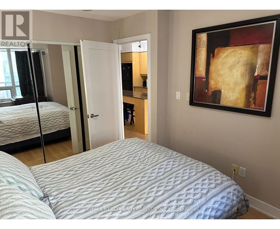 A bedroom with a bed, a mirror, and a painting on the wall.