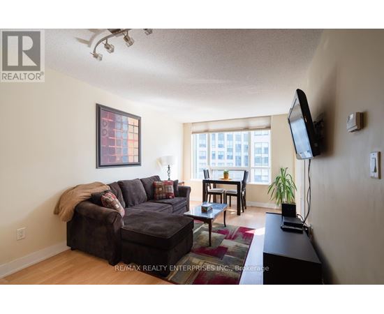 A living room with a brown couch and a flat screen TV mounted on the wall.