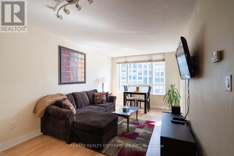 A living room with a brown couch and a flat screen TV mounted on the wall.