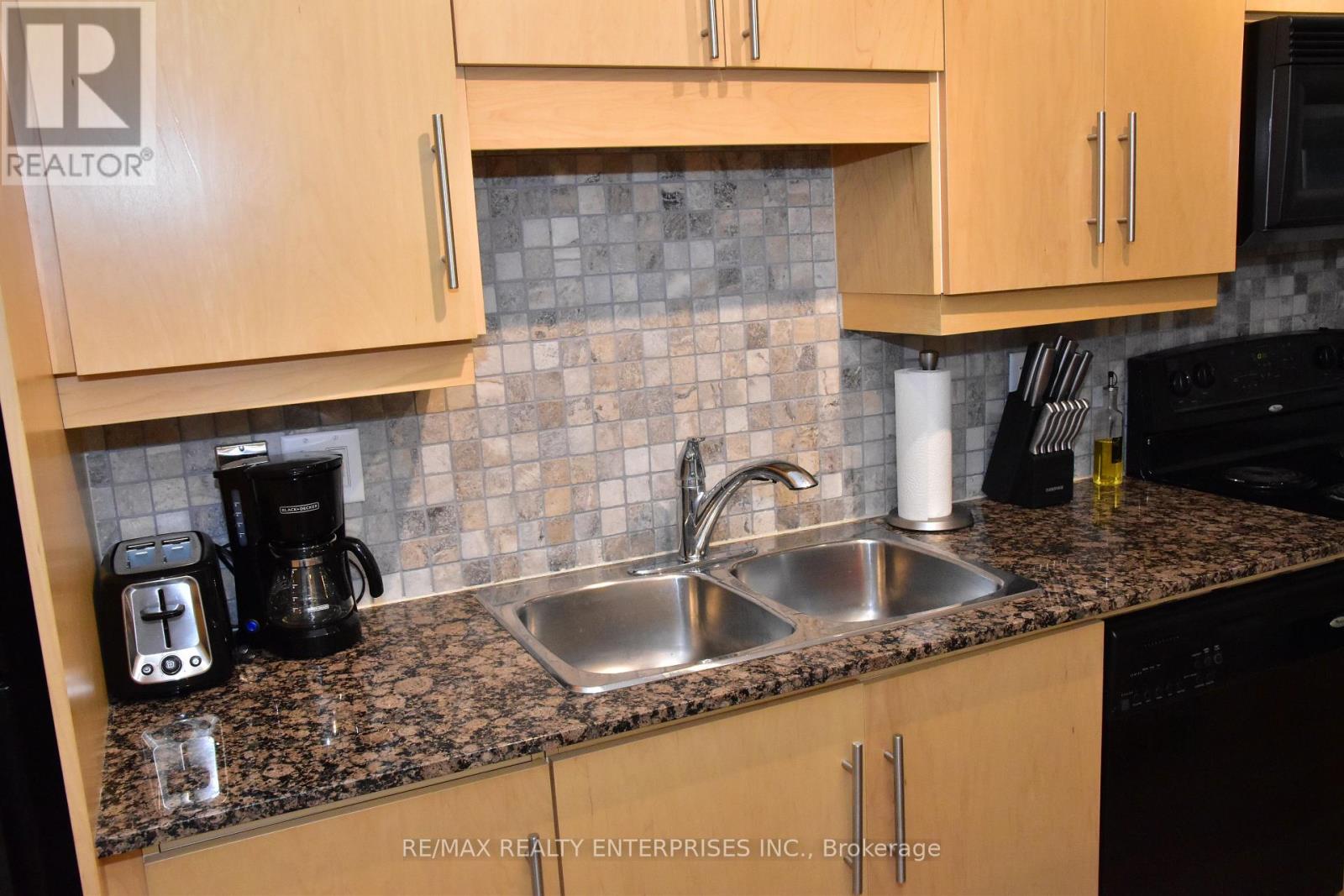 A kitchen with a sink, coffee maker, and cabinets.