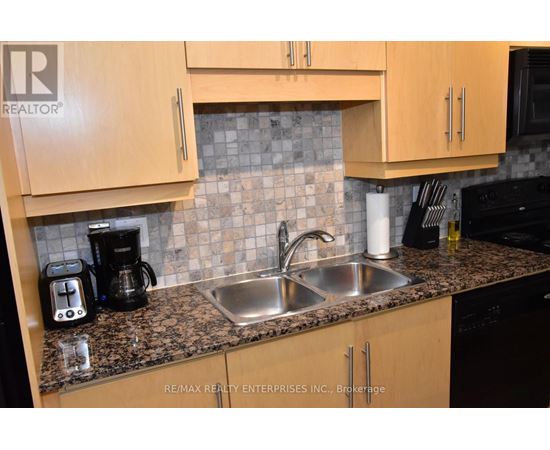 A kitchen with a sink, coffee maker, and cabinets.