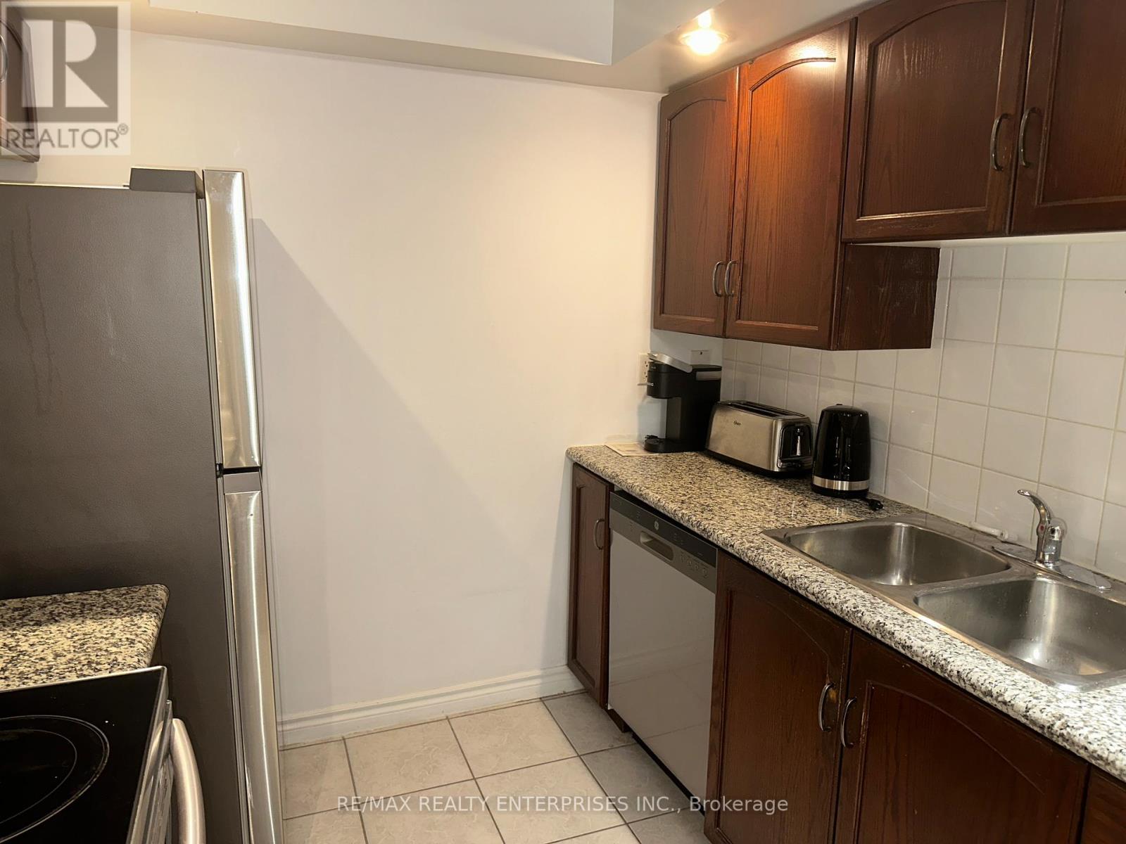 A kitchen with a refrigerator, sink, and countertop.