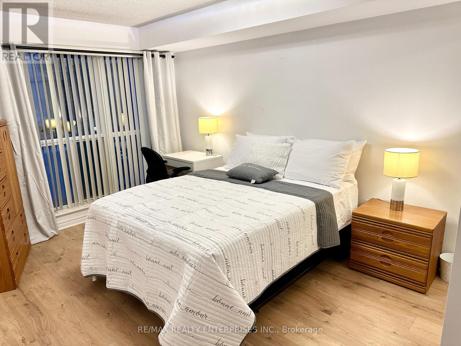 A bedroom with a large bed and a wooden nightstand.