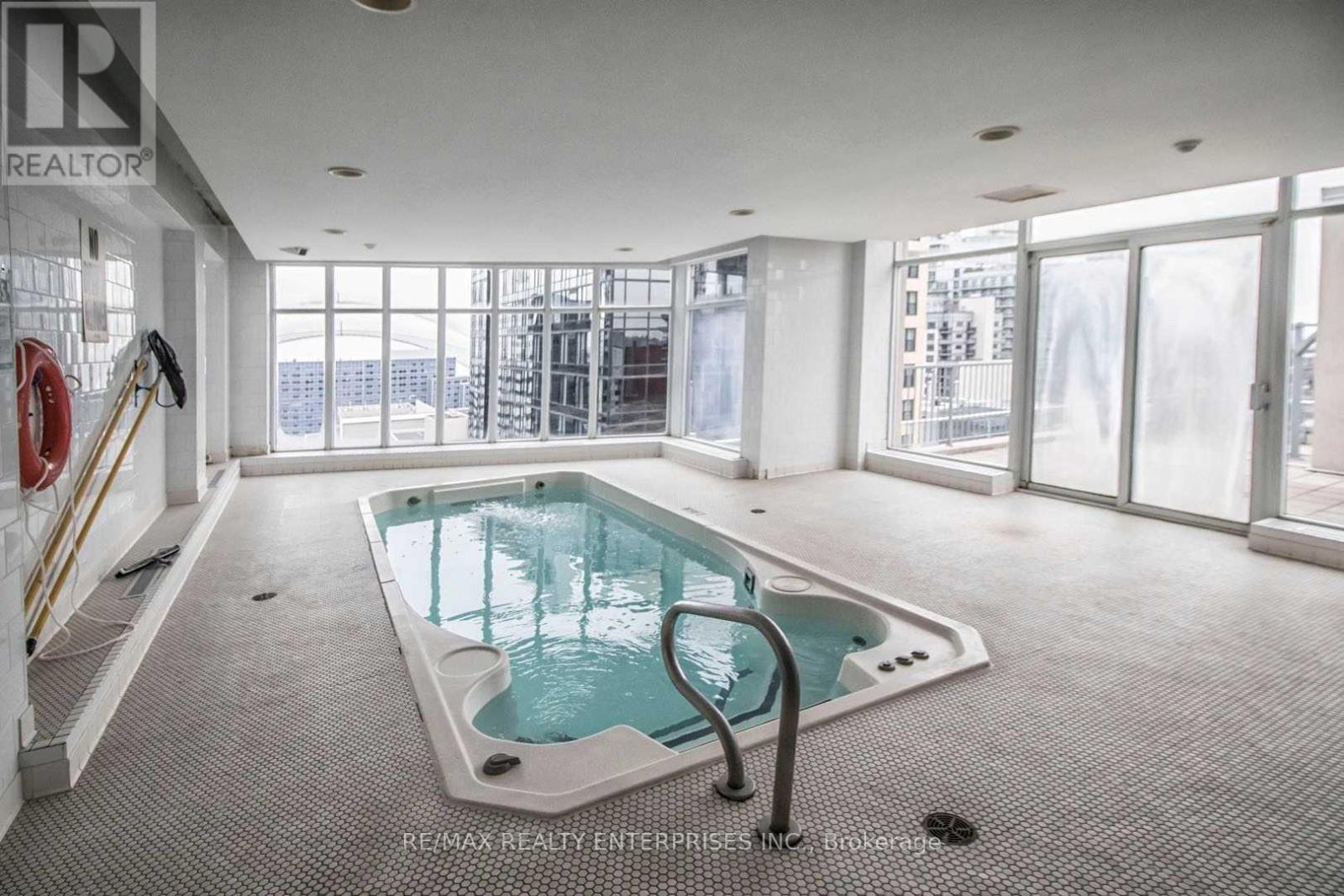A large indoor pool with a glass enclosure and a metal ladder.