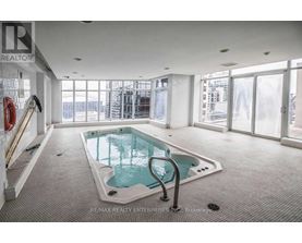 A large indoor pool with a glass enclosure and a metal ladder.