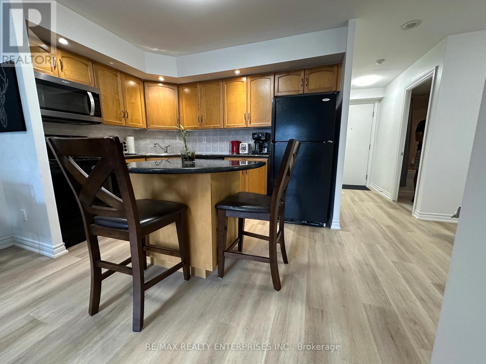 A kitchen with wooden cabinets and a black refrigerator.