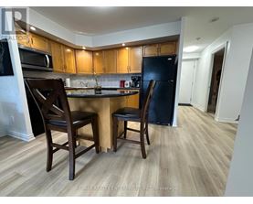 A kitchen with wooden cabinets and a black refrigerator.