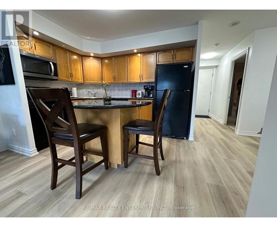 A kitchen with wooden cabinets and a black refrigerator.