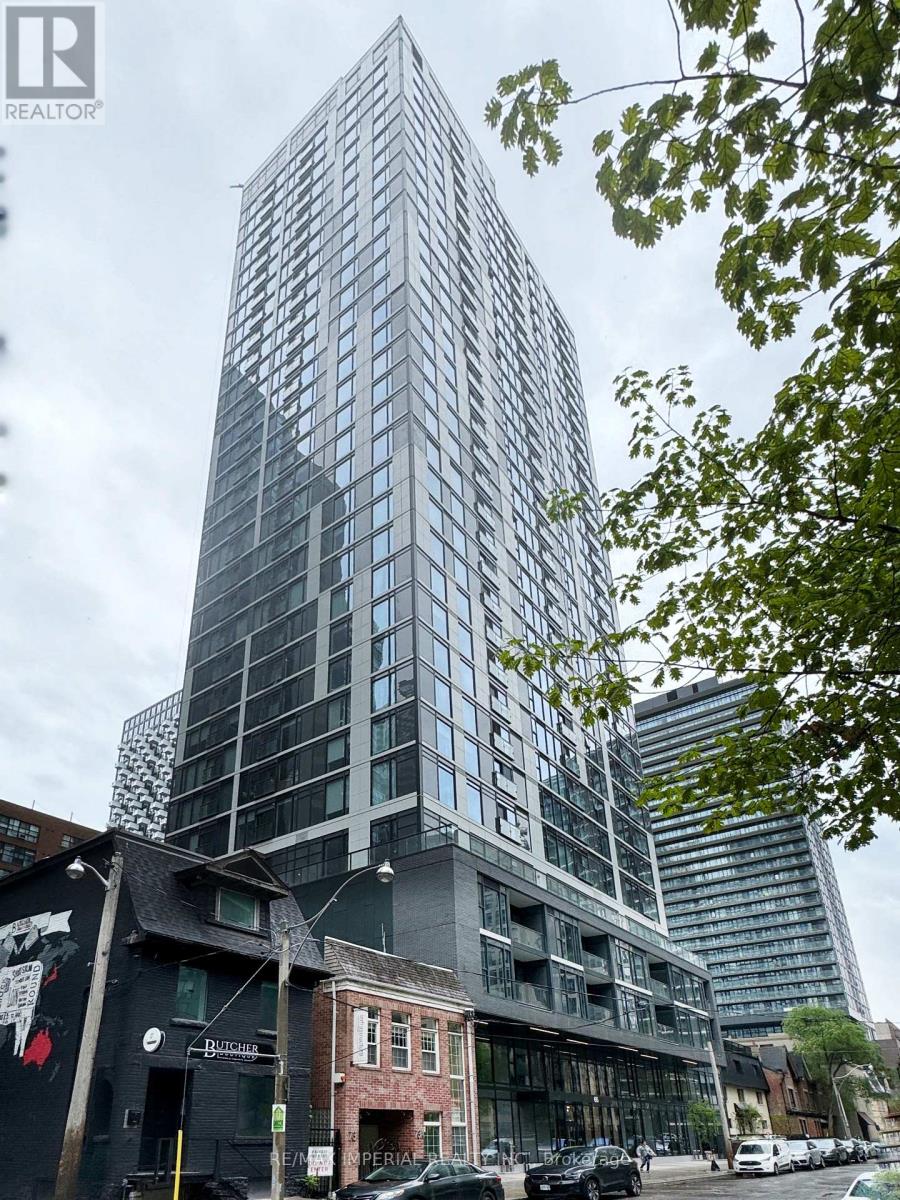 A tall glass building stands in front of a smaller building with a black facade.