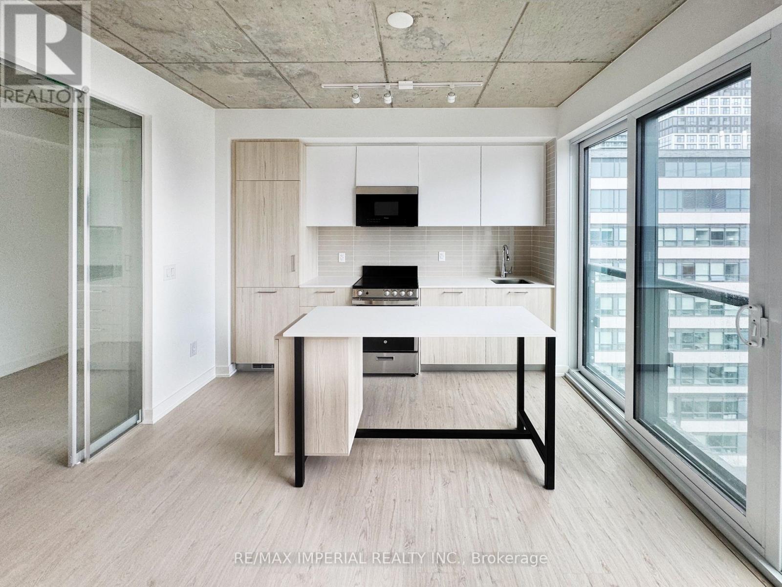 A modern kitchen with a table and chairs in the foreground and a glass door leading to a balcony.