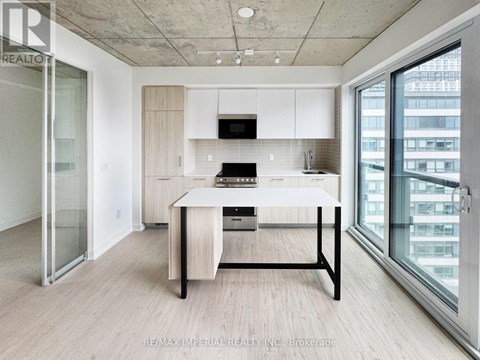 A modern kitchen with a table and chairs in the foreground and a glass door leading to a balcony.