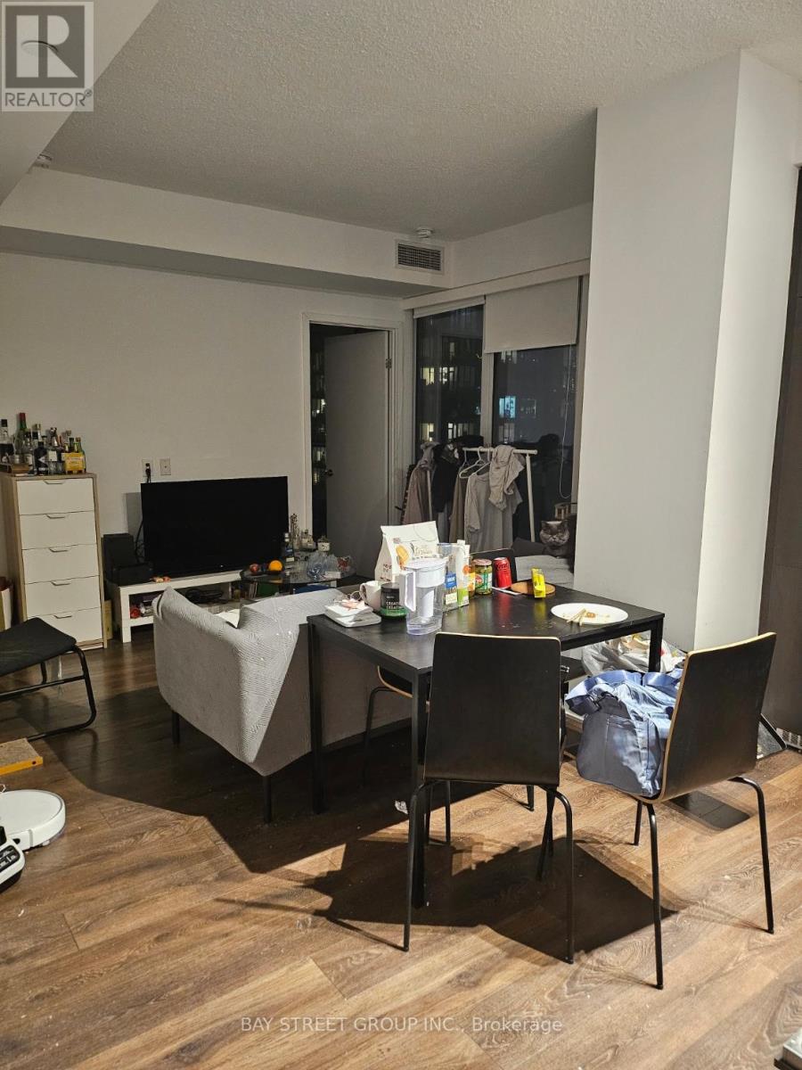 A living room with a grey couch, a black chair, and a dining table with chairs.