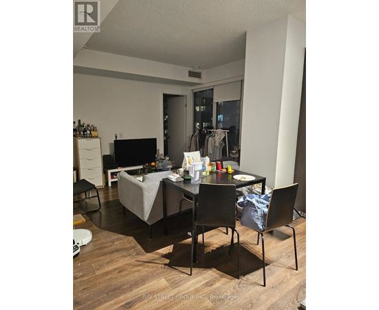A living room with a grey couch, a black chair, and a dining table with chairs.