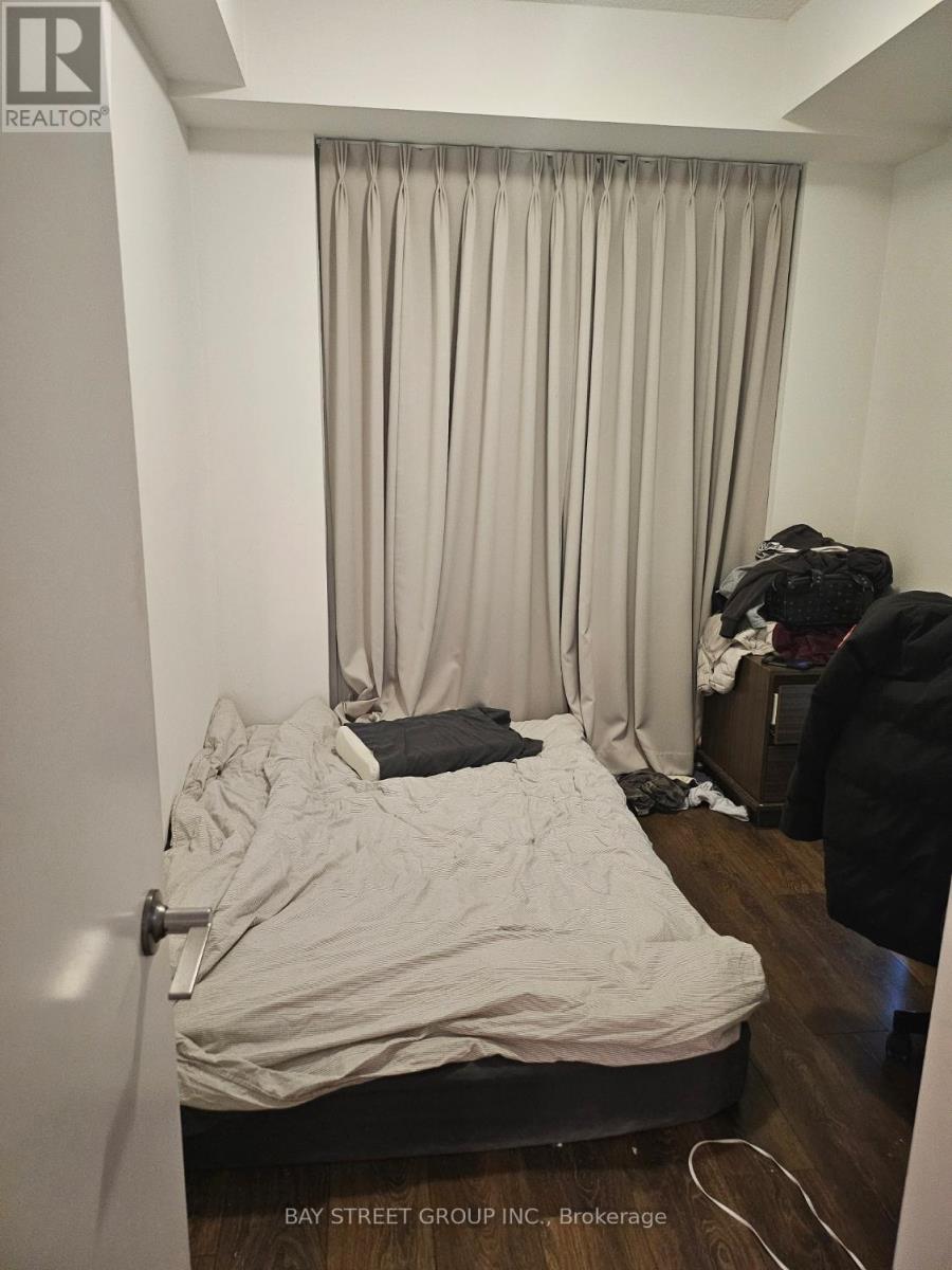 A bedroom with a bed, a chair, and a window with curtains.