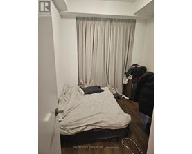 A bedroom with a bed, a chair, and a window with curtains.