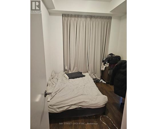 A bedroom with a bed, a chair, and a window with curtains.