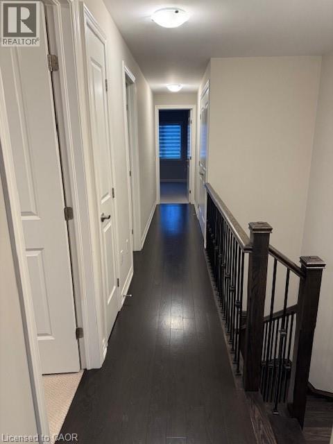 A long hallway with white doors and a black railing.