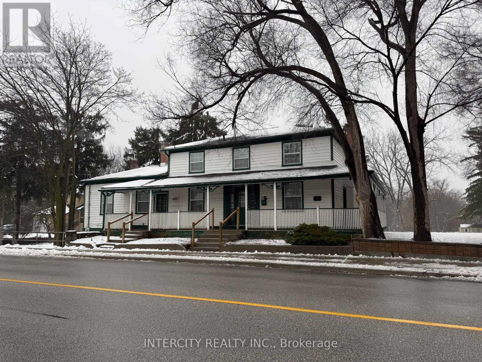 A house with a white siding and a porch is shown in the image.