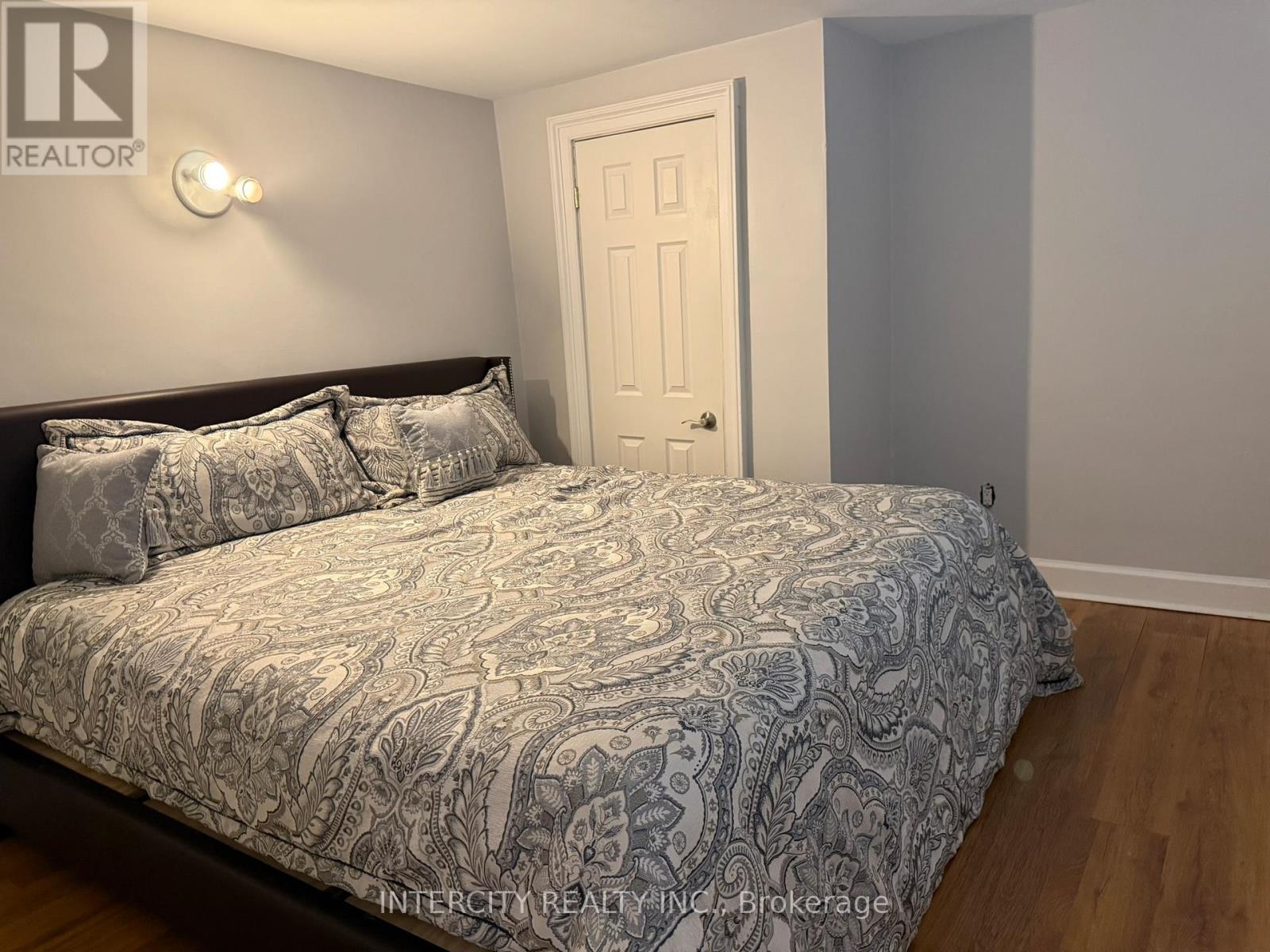 A bedroom with a bed, pillows, and a door.