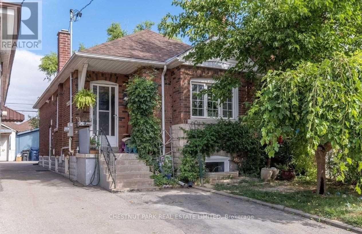 A brick house with a porch and a tree in front.