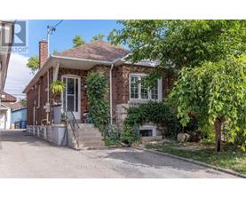 A brick house with a porch and a tree in front.