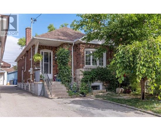 A brick house with a porch and a tree in front.
