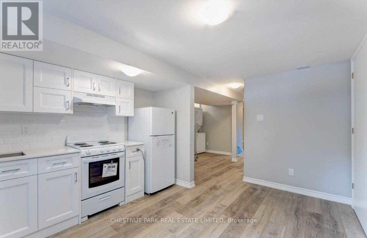 A kitchen with white appliances and cabinets in a real estate listing.