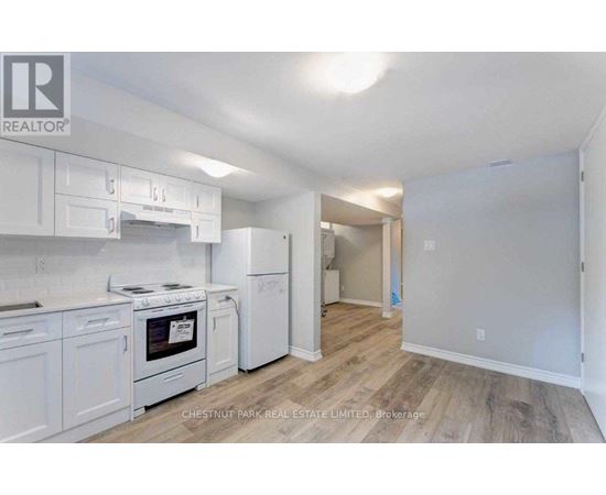 A kitchen with white appliances and cabinets in a real estate listing.