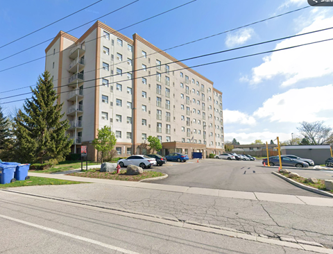 A large apartment building with a parking lot in front.