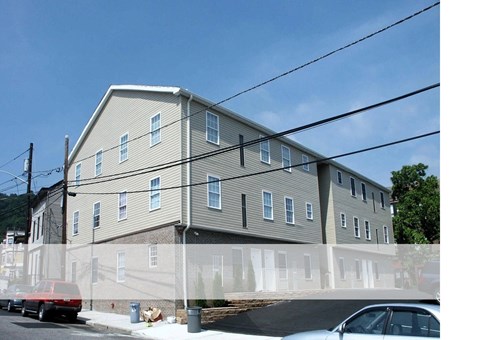 A grey building with a red truck parked in front.
