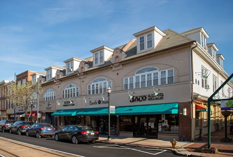 A street view of a row of buildings with cars parked in front.