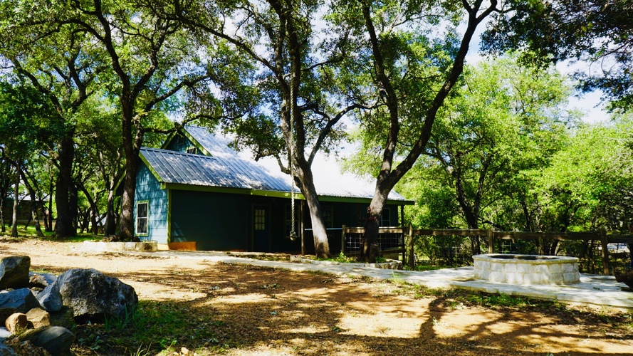 A blue shed sits in a grassy area with trees in the background.