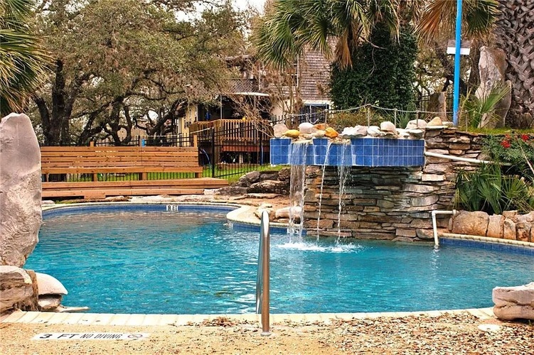 A pool with a waterfall and a bench.