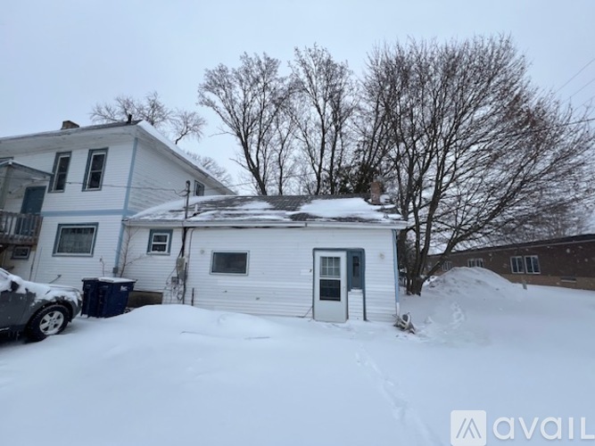 A house with a car parked in front of it is covered in snow.