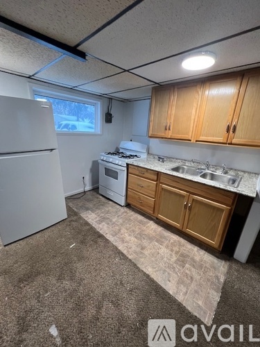 A kitchen with a white refrigerator, wooden cabinets, and a window.