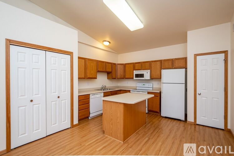A kitchen with white appliances and wooden cabinets.