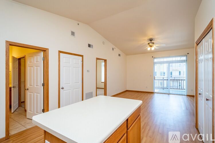 A spacious room with wooden floors and white walls, furnished with a large white table and multiple doors.