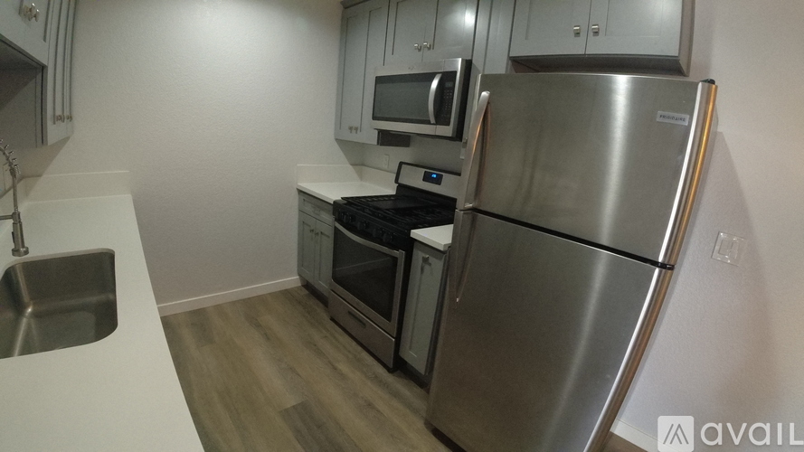 A kitchen with a stainless steel refrigerator, microwave, oven, and sink.