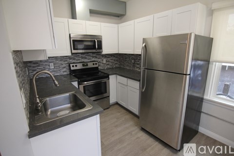 A kitchen with a stainless steel refrigerator, microwave, oven, and sink.
