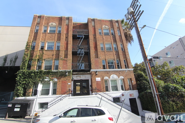 A white car is parked in front of a red brick building.