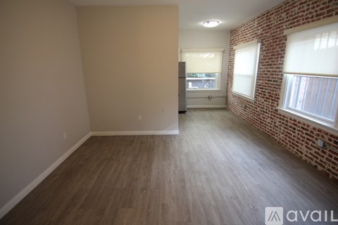 A room with wooden flooring and a brick wall.