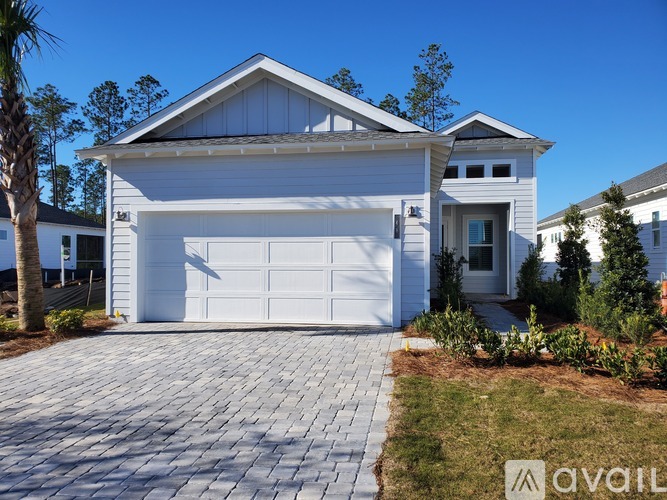 A white house with a garage door and a driveway.